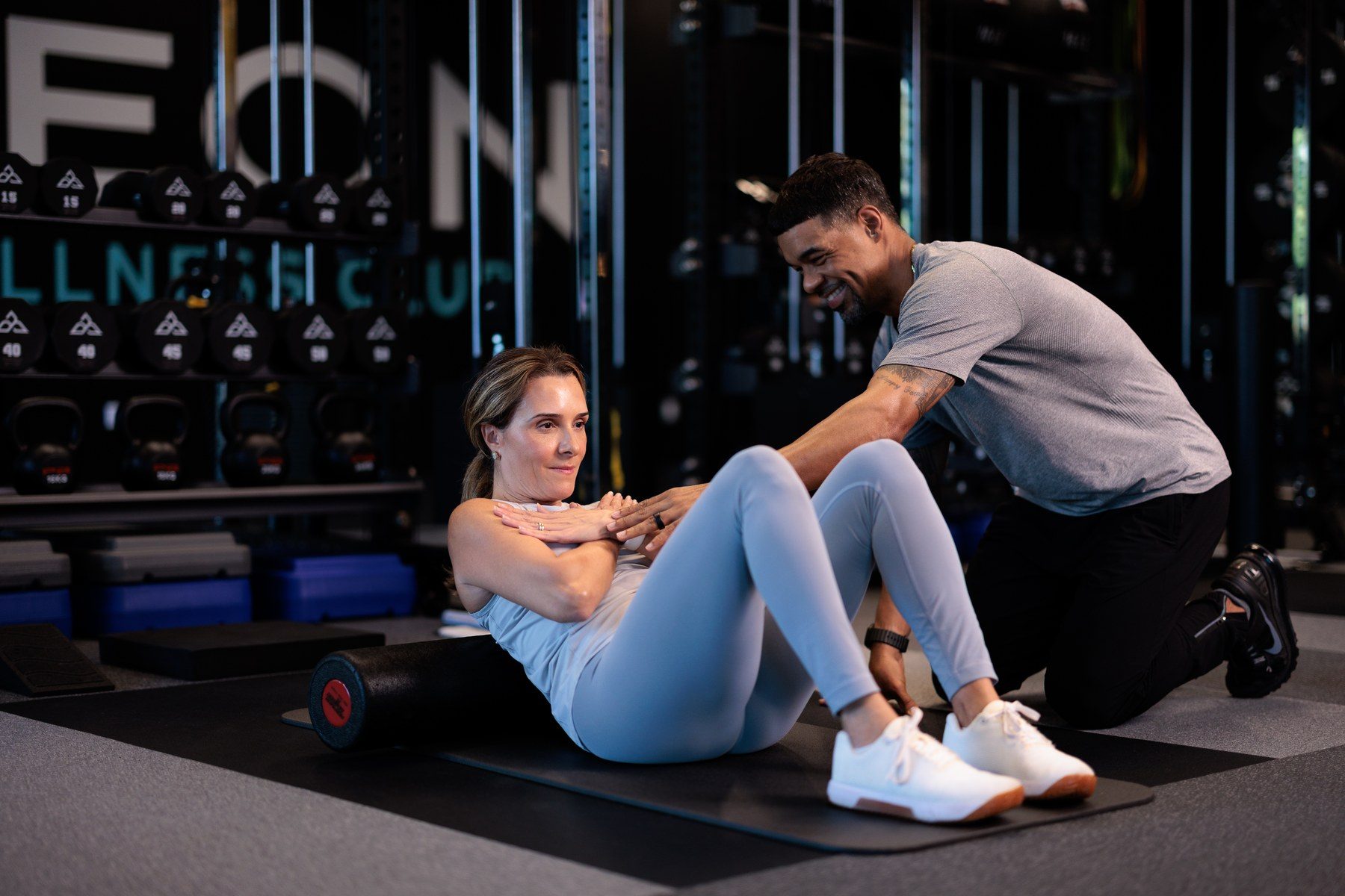 An Aeon Wellness Club coach guiding a member through a core exercise on the Alpharetta training floor